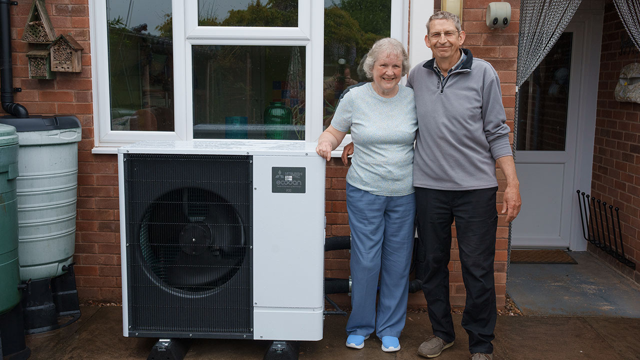 Andrew and Sue standing outside their home at their Mitsubishi heat pump