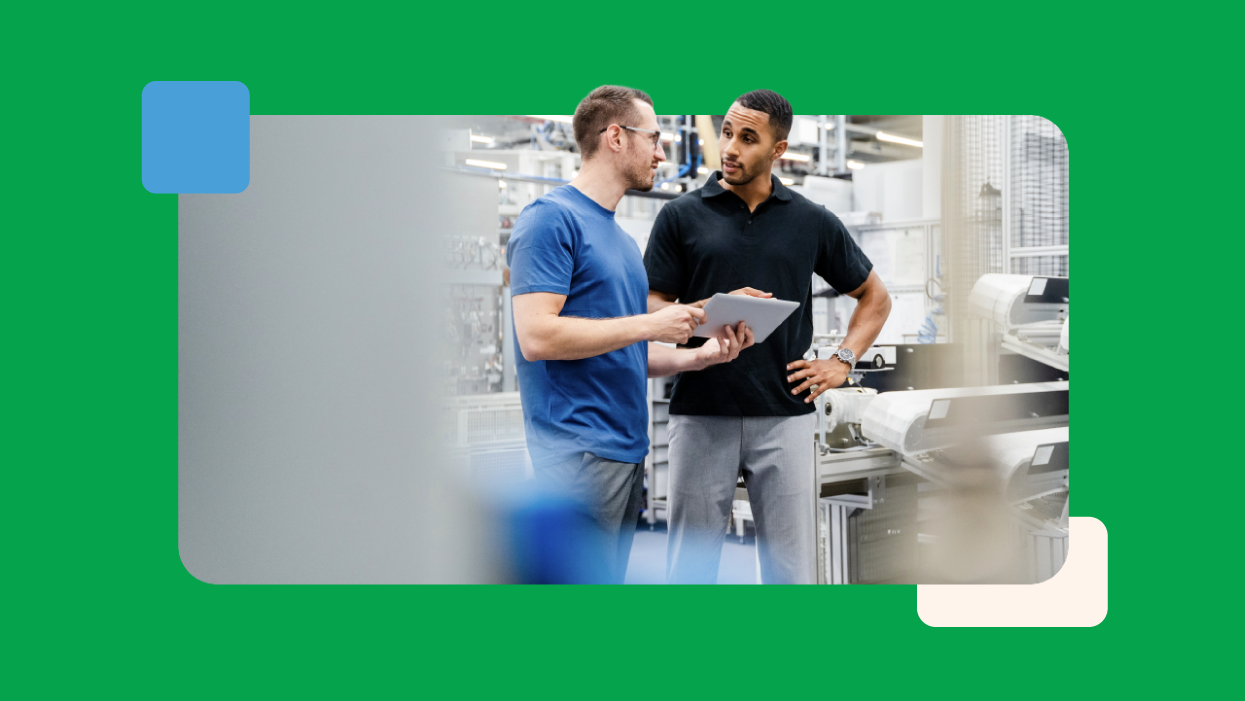 Manufacturing employees reviewing production data on a tablet in a modern industrial facility, supporting efficient operations, process improvement and sustainable manufacturing practices.