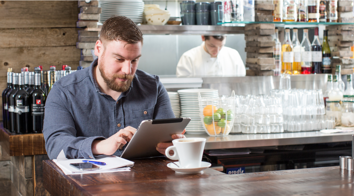 man standing looking at tablet in restaurant 