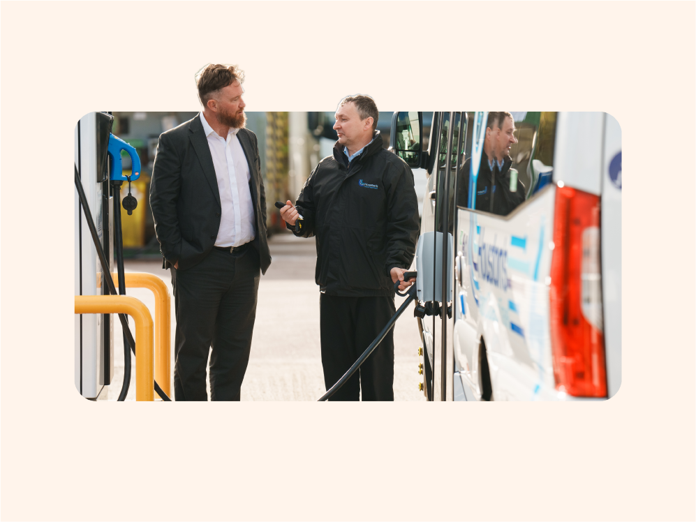 Two men standing beside an electric bus charging