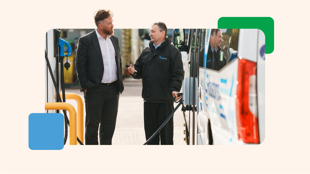 Two men standing beside an electric bus charging