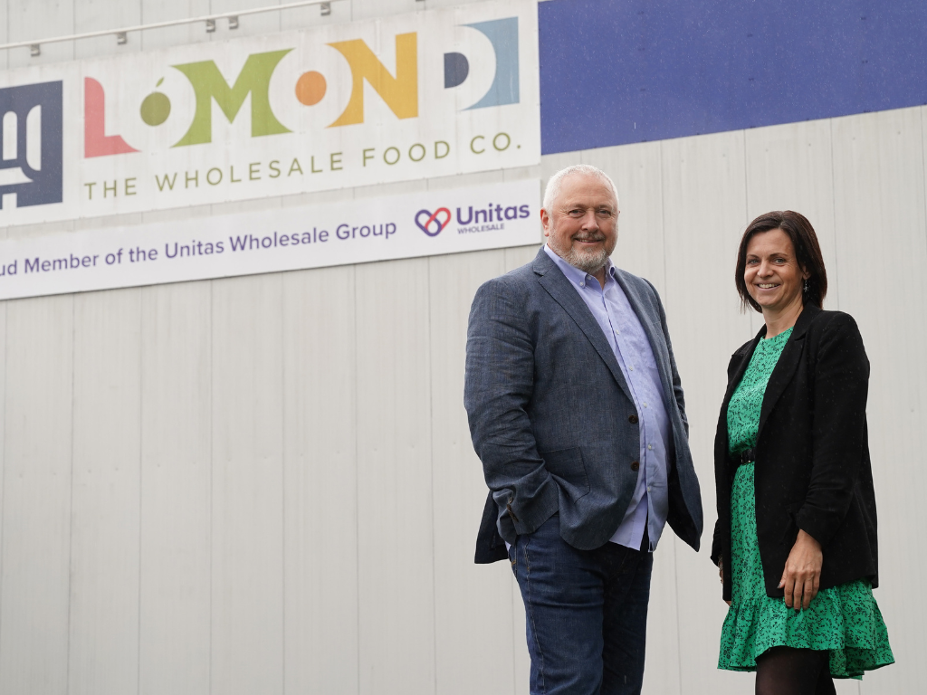 Two people standing outside a wholesale food company premises, highlighting business partnerships, energy innovation and collaboration to support sustainable business operations.