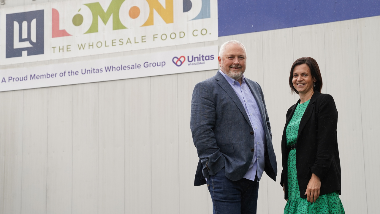 Two people standing outside a wholesale food company premises, highlighting business partnerships, energy innovation and collaboration to support sustainable business operations.