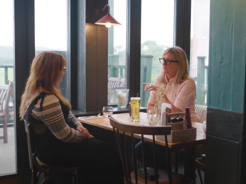 Two people meeting in a café to discuss services and customer needs, illustrating community engagement, customer experience and local business relationships.