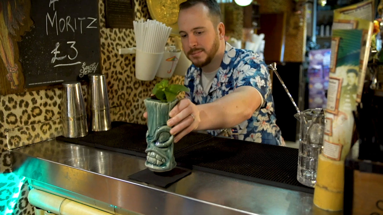 Person preparing a drink behind a bar, highlighting hospitality services, customer experience and support for local businesses in the food and drink sector.