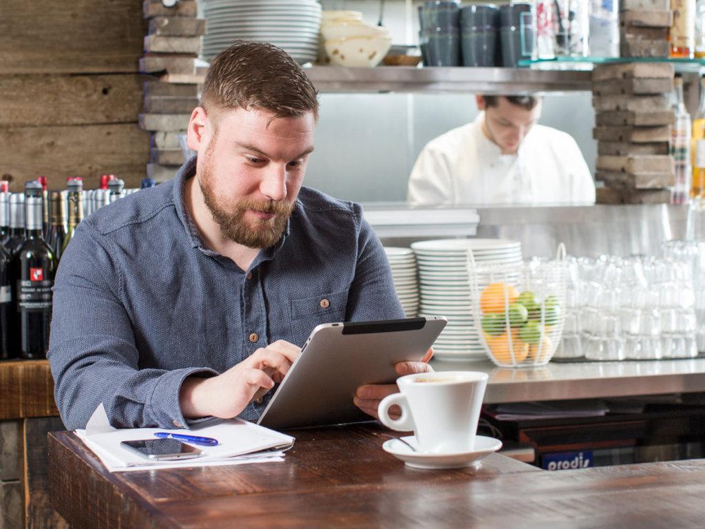 man sitting in a cafe using his tablet