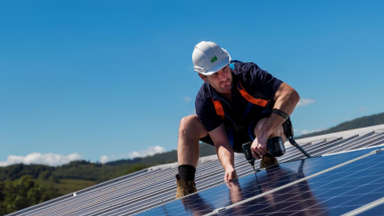 man installing solar panels on a roof