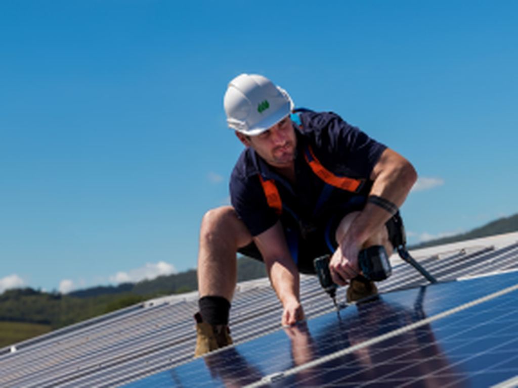 man installing solar panels on a roof