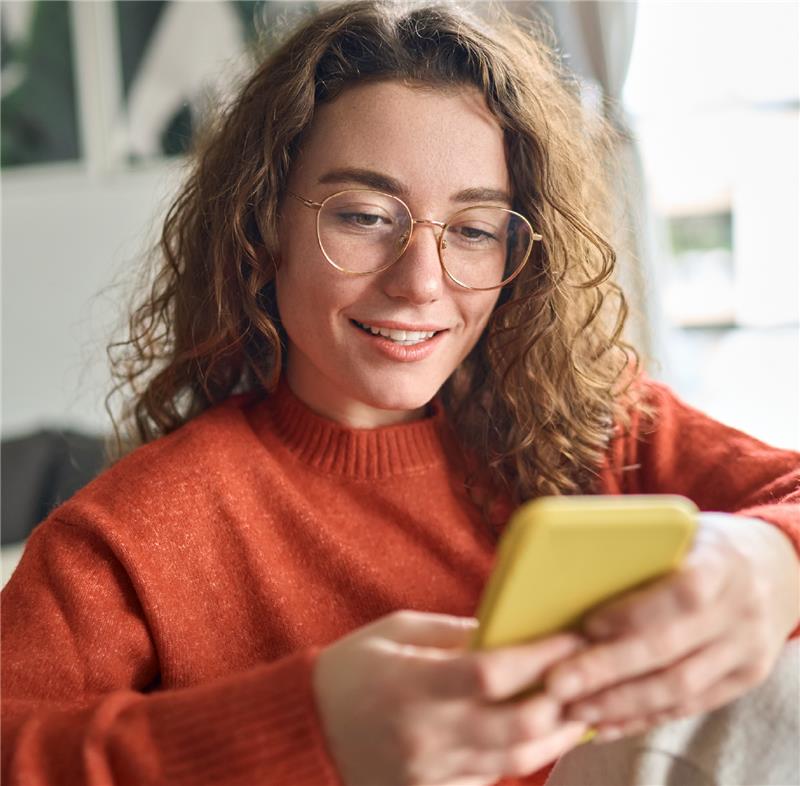 Women sitting on the couch on scrolling on her phone