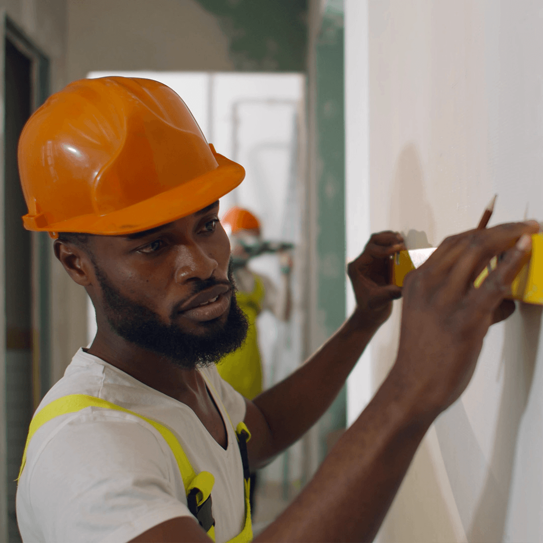 Construction worker measuring and marking an interior wall during a building renovation project.