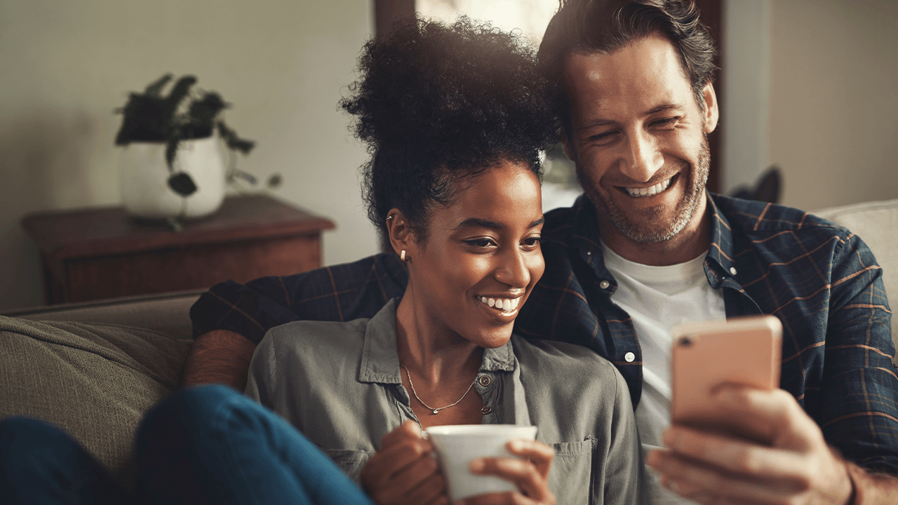 Couple sitting on the couch looking at mobile phone