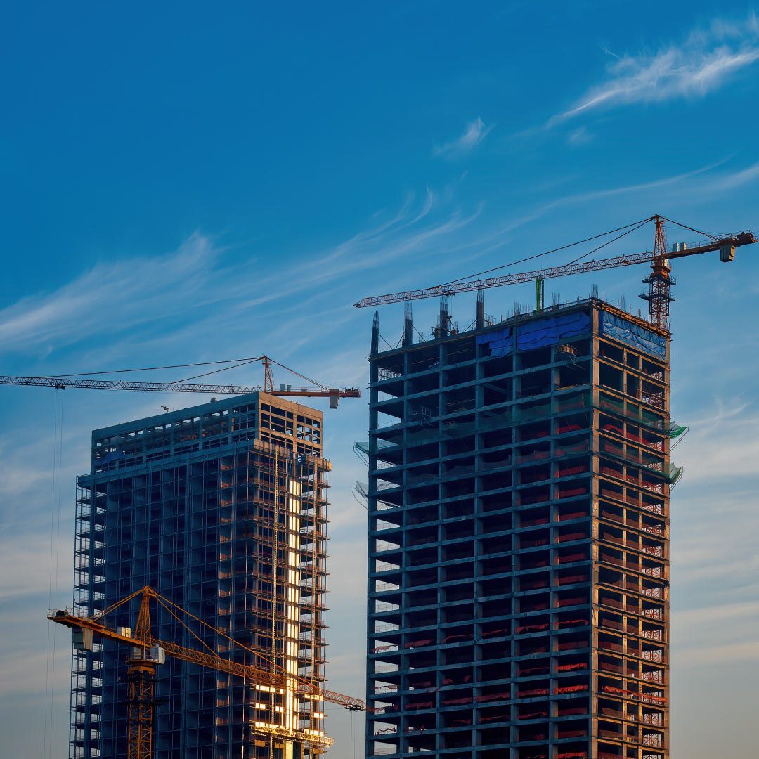 High-rise buildings under construction with cranes at a city development site.