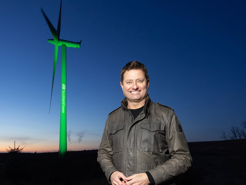 George Clarke standing in front of turbine lit up with ScottishPower branding.