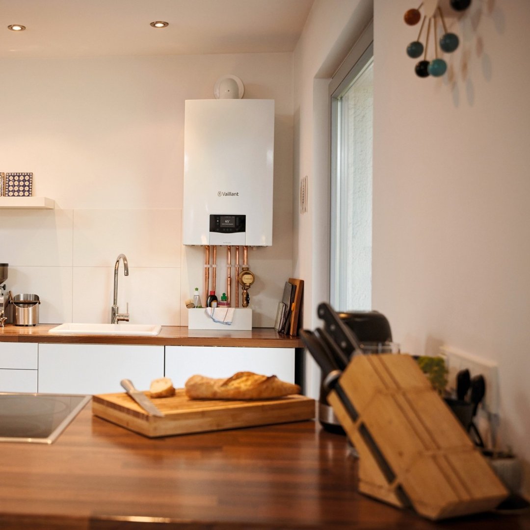 Wall‑mounted boiler installed above a kitchen counter, with a sink and kitchen items below.