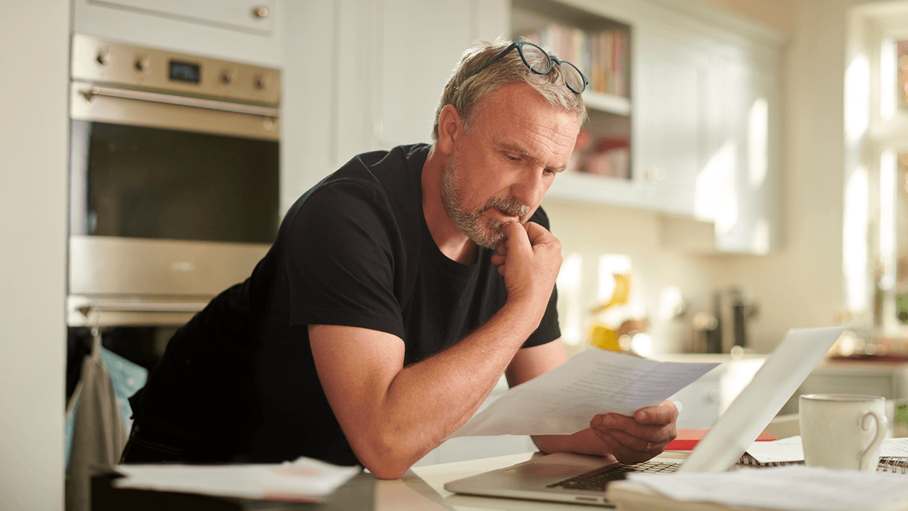 man standing in kitchen reading a document