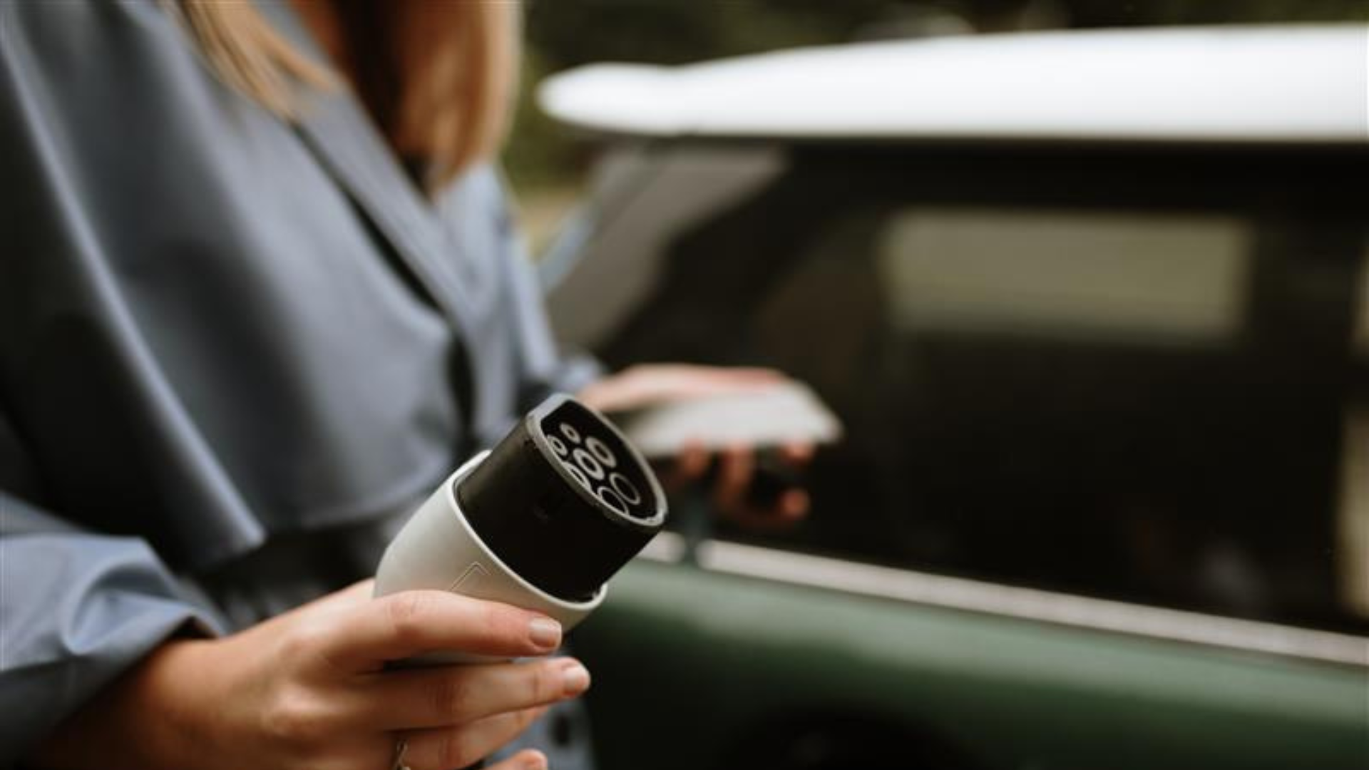 women plugs in EV charger