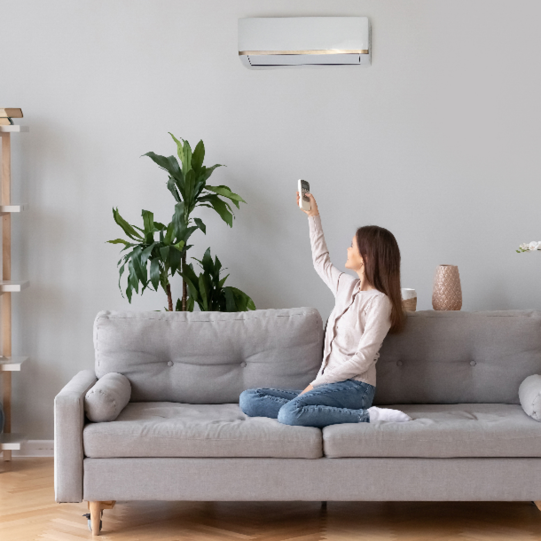 Person controls BOXT air conditioning unit whilst sitting on couch