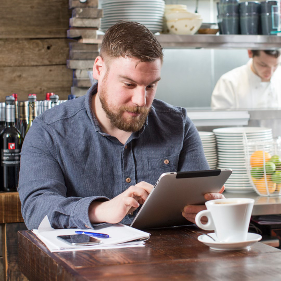 man sitting in a cafe looking at ipad