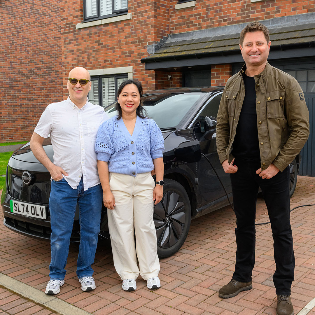 George standing outside on a driveway with a couple who are ScottishPower customers. They are standing next to their electric car.
