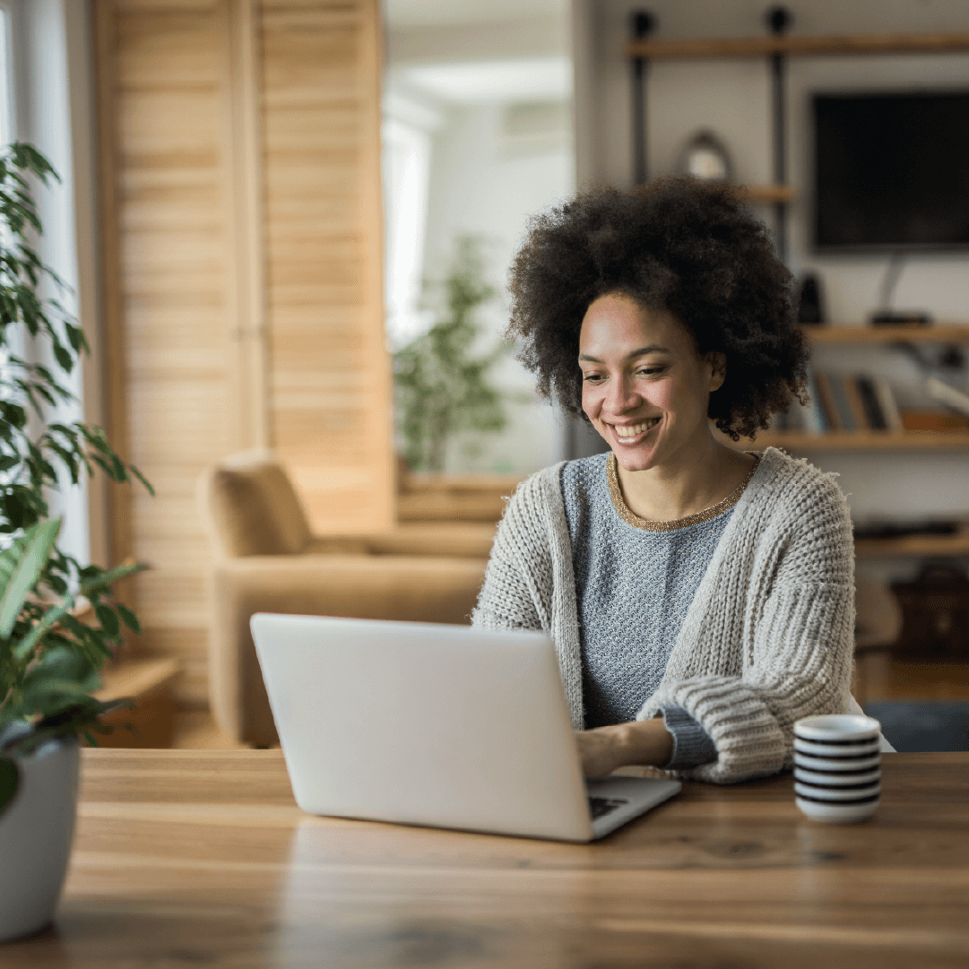 Woman using a laptop at a wooden table in a living room